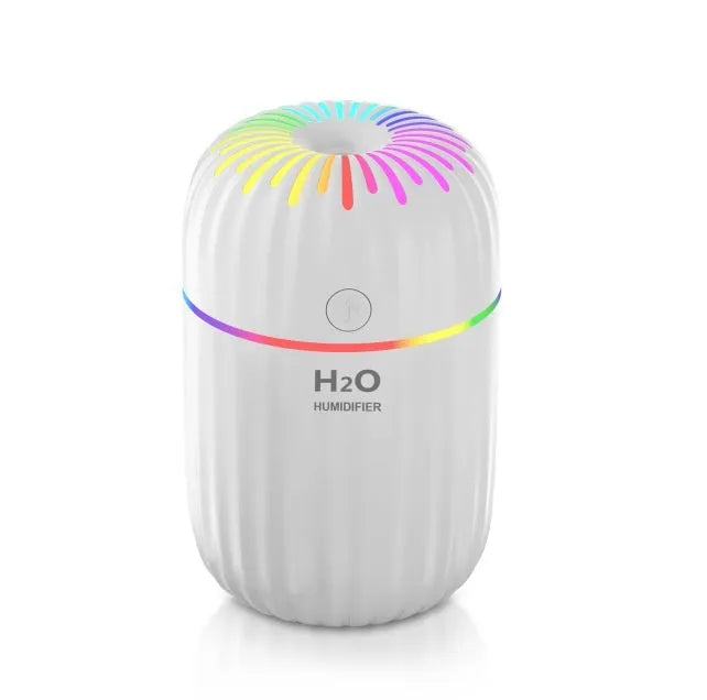 Small white USB-powered mini humidifier with water tank on a desk next to a laptop.