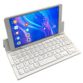 Black folding Bluetooth keyboard unfolded next to tablet showing ultra-thin design