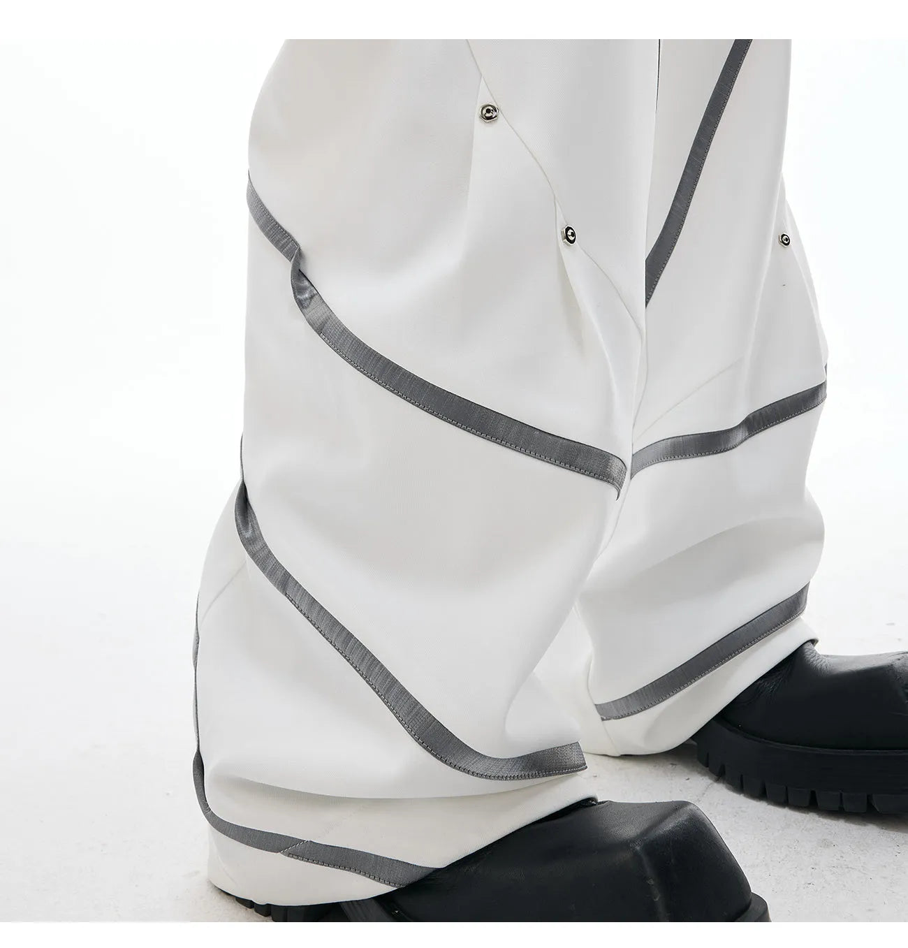 Men's black trousers with silver metal striped rivet details and pleated front.