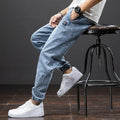 Men's loose-fit cargo jeans in blue, showing straight leg and mid-waist design on a hanger.