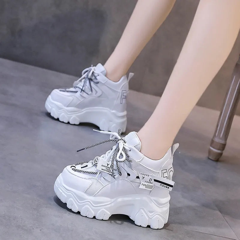 Women's white low-top platform trainers with mesh panels and a black cross-strap over the vamp.