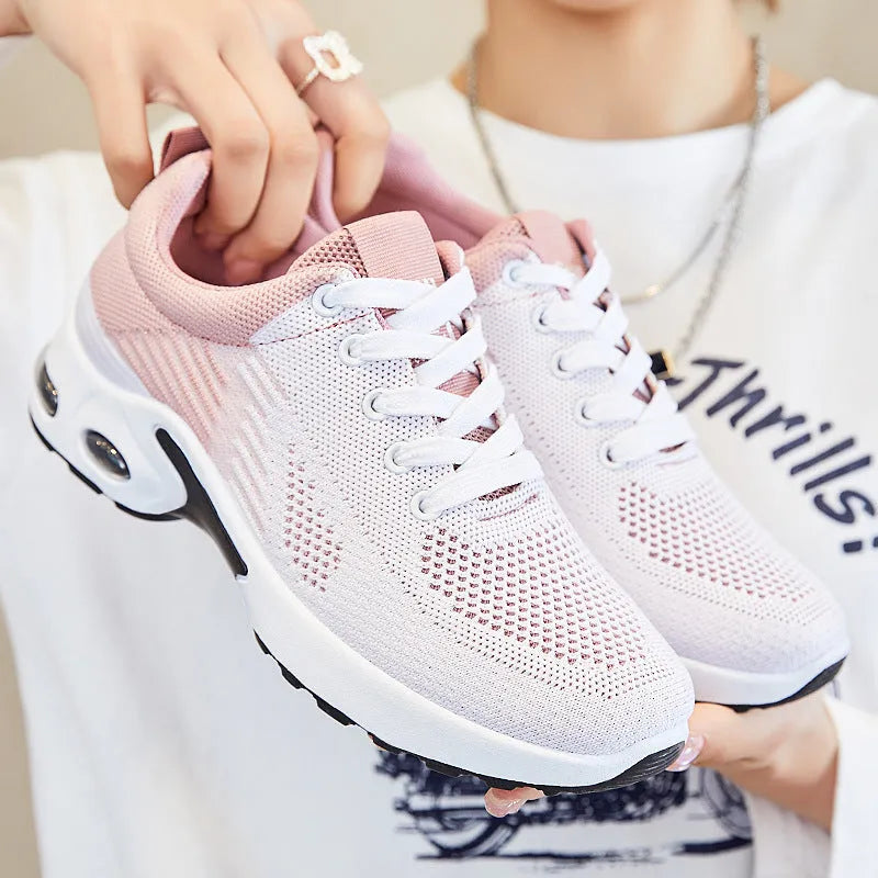 Women's pink Flyknit casual running shoes with mesh lining and flat PVC sole on a white background.