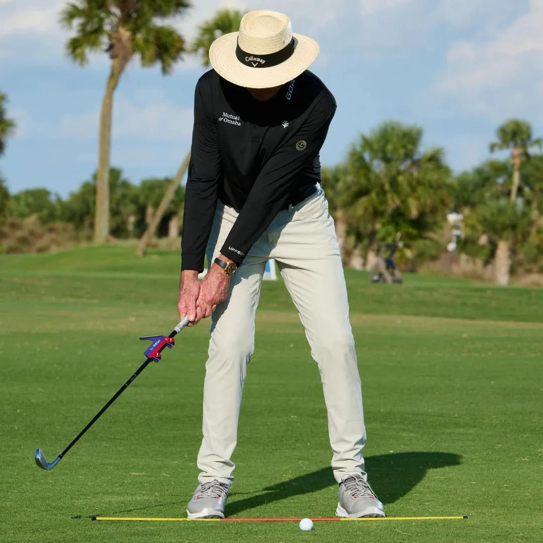 Plastic golf swing plane simulator training aid on a green surface.