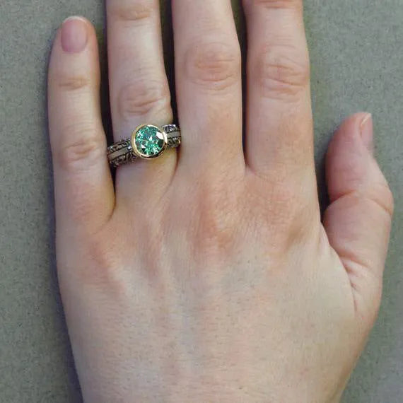 Flower-shaped vintage ring with gold-plated details and a green gemstone on a silver-toned alloy band.