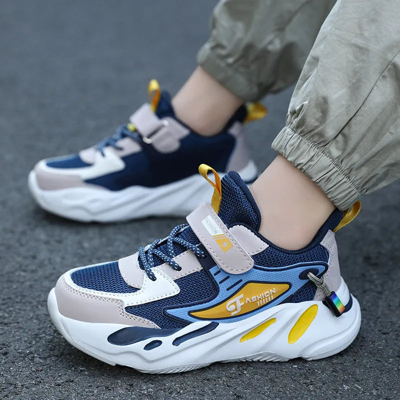 Boys' blue and black platform sports running shoes with Velcro straps on a hard ground surface.