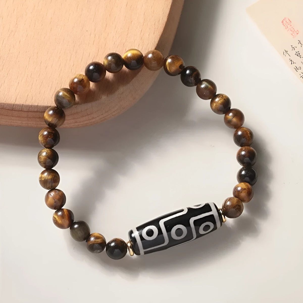 Tigereye stone bead bracelet with a single central Dzi bead featuring a circle design.