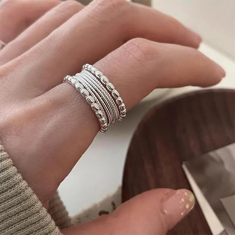 Copper adjustable ring with a woven twisted multilayer geometric design on a finger.