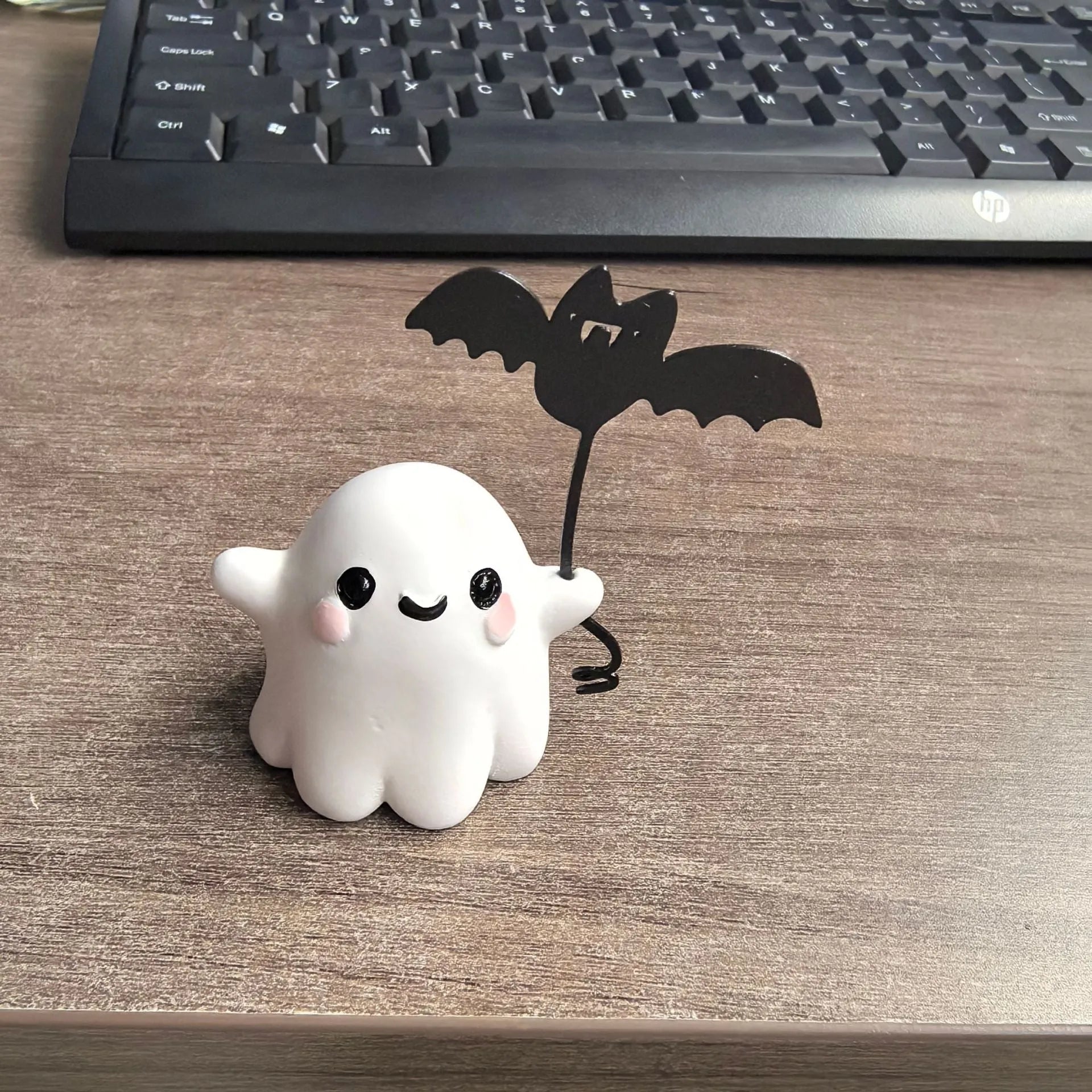 Miniature resin statue of a ghost walking a dog and holding a bat, a 4cm tall Halloween decoration.