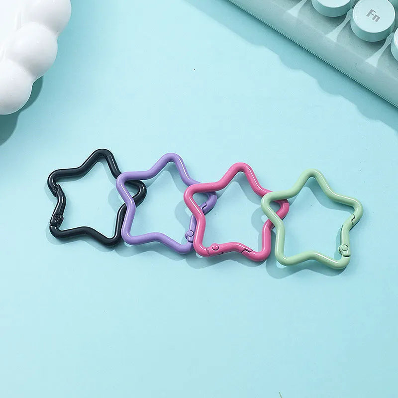 Zinc alloy five-pointed star keychain charm in assorted colours including light pink, blue, and black.
