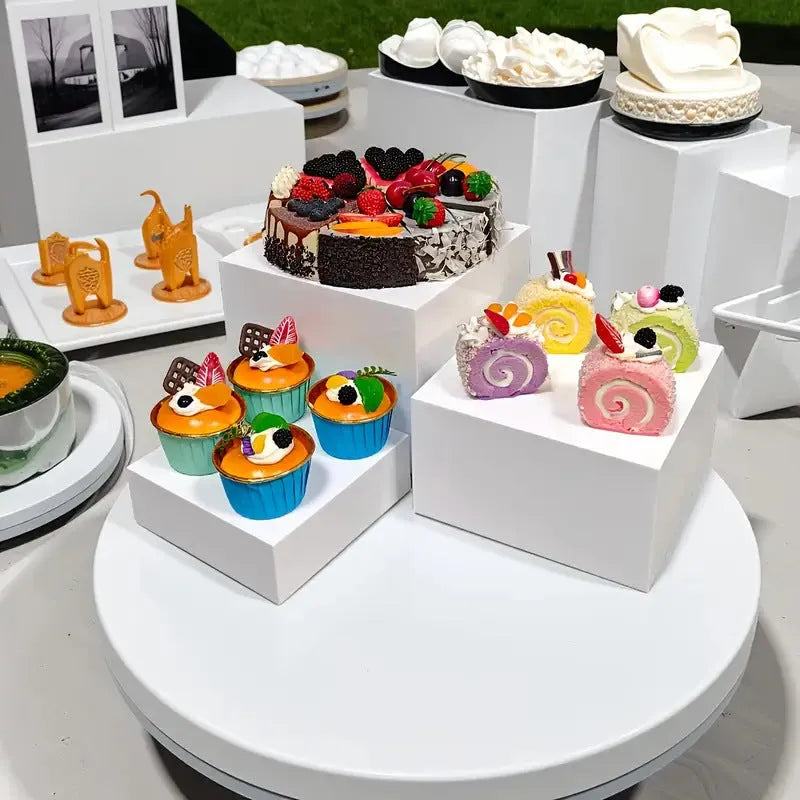 Set of six white plastic cube display stands arranged on a wooden tabletop.