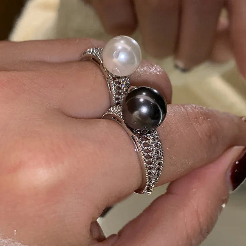 Geometric adjustable open ring in black pearl colour on a copper band, shown on a woman's index finger.