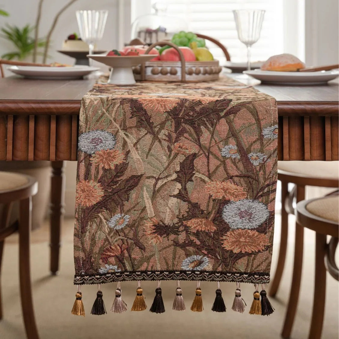 Long beige table runner with floral Jacquard pattern and tassels, shown on a wooden table.