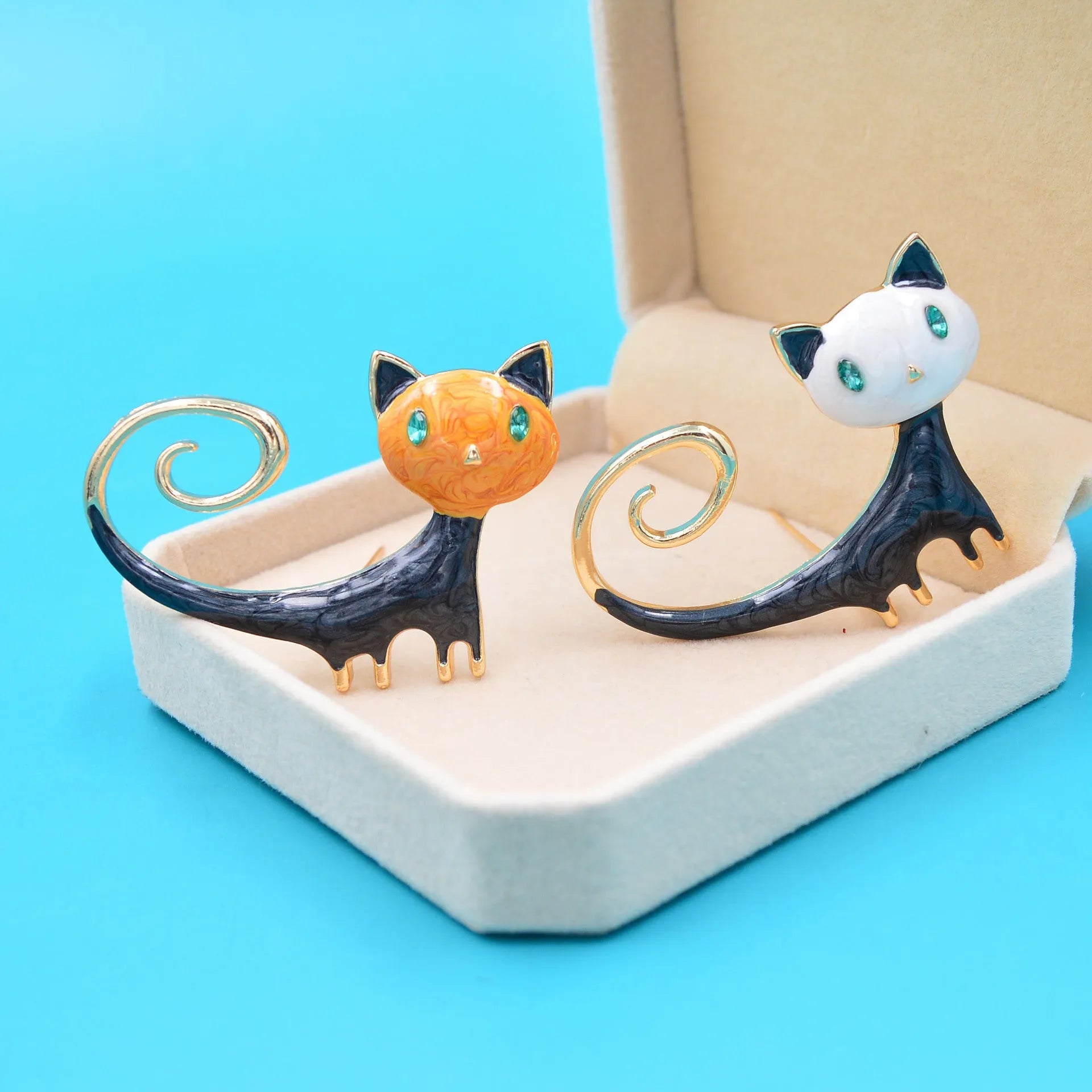 Close-up of a hand-painted tail-up kitten brooch in alloy metal, on a white background.