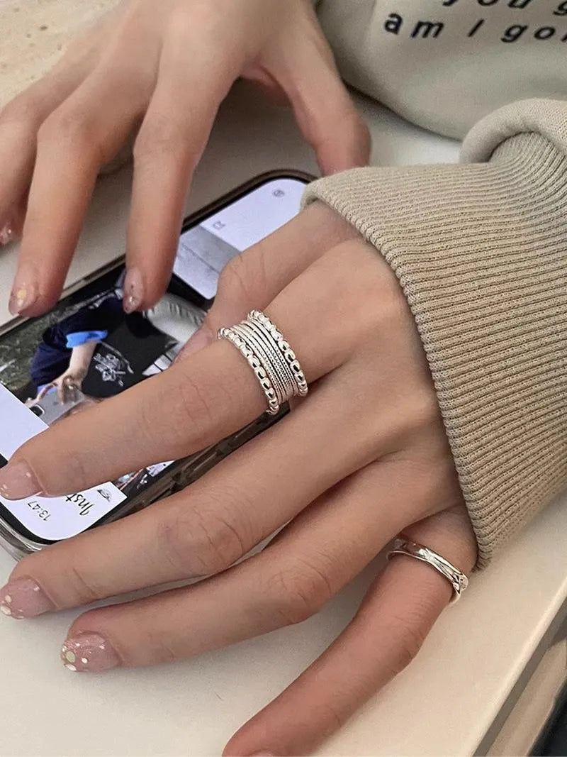 Copper adjustable ring with a woven twisted multilayer geometric design on a finger.