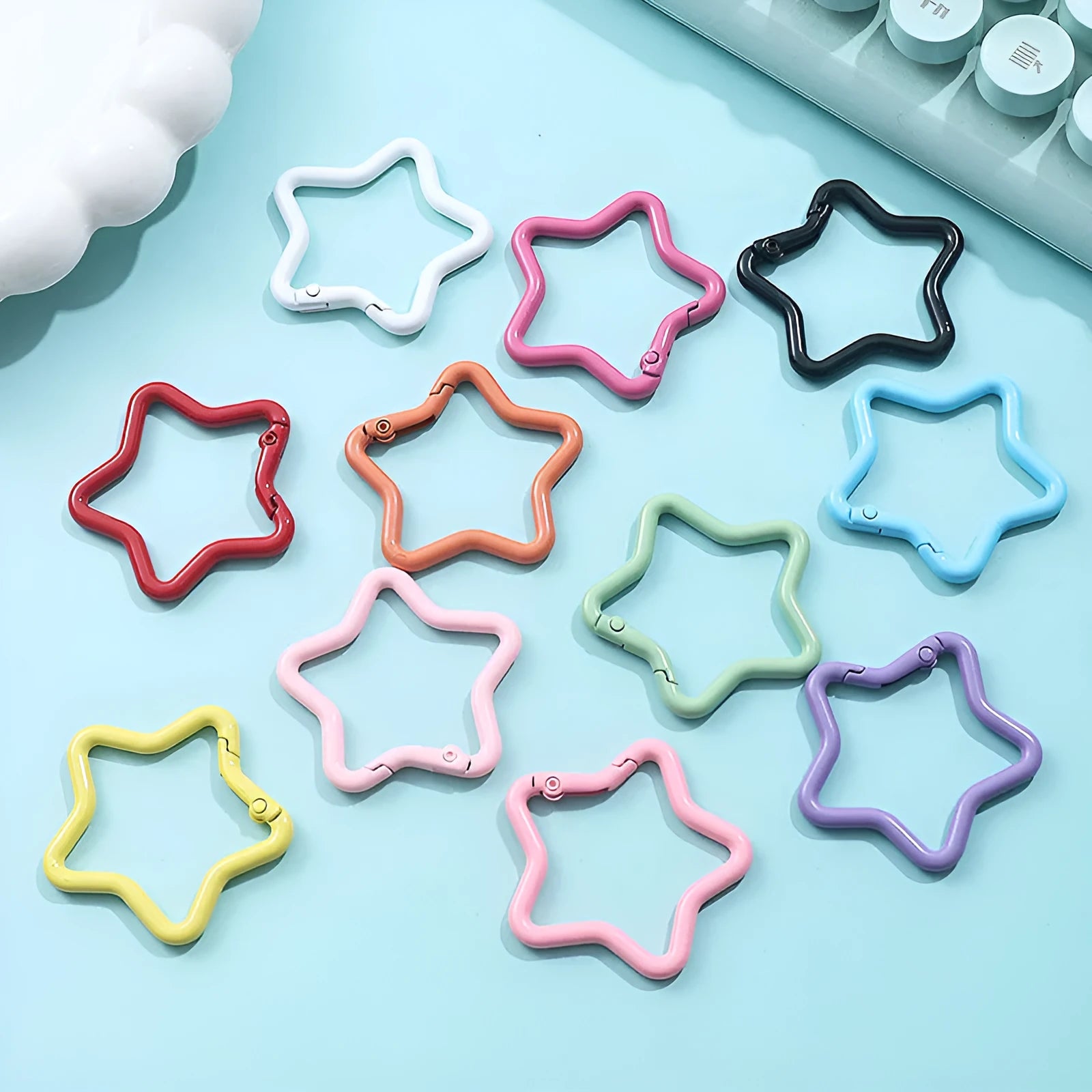 Zinc alloy five-pointed star keychain charm in assorted colours including light pink, blue, and black.
