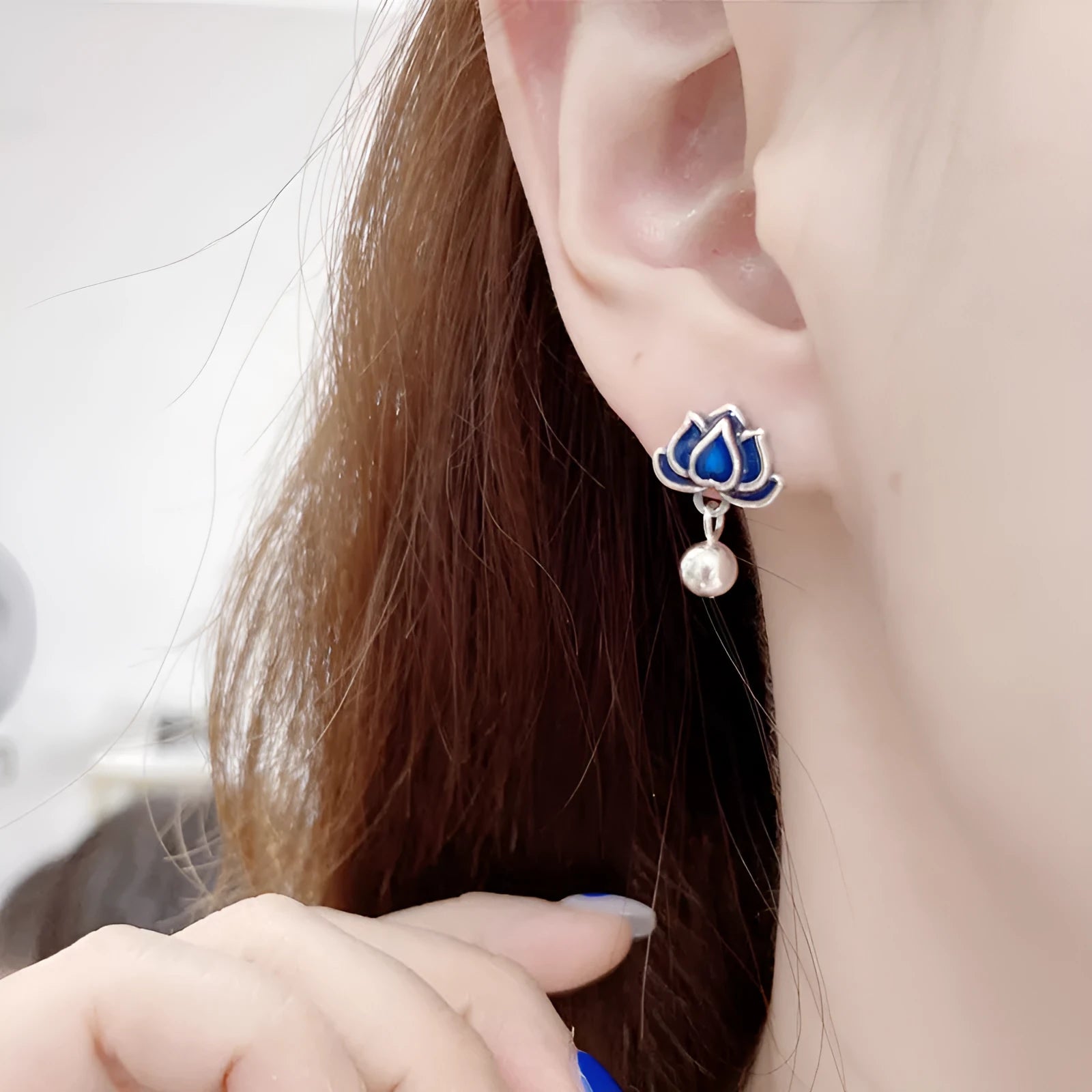 Close-up of blue lotus seedpod and tassel drop earrings in silver tone alloy on a white background.