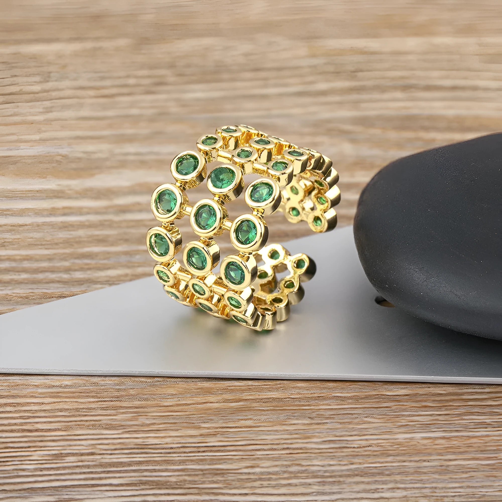Copper ring with gold plating and green zircon stones in a wide exaggerated band.