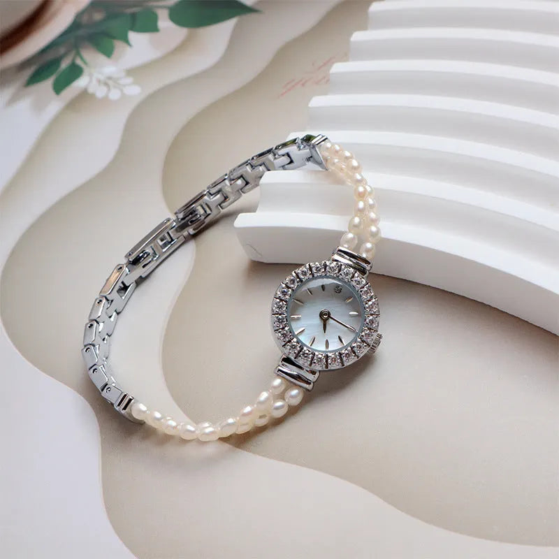 Women's light gold freshwater pearl bracelet watch with round dial on wrist
