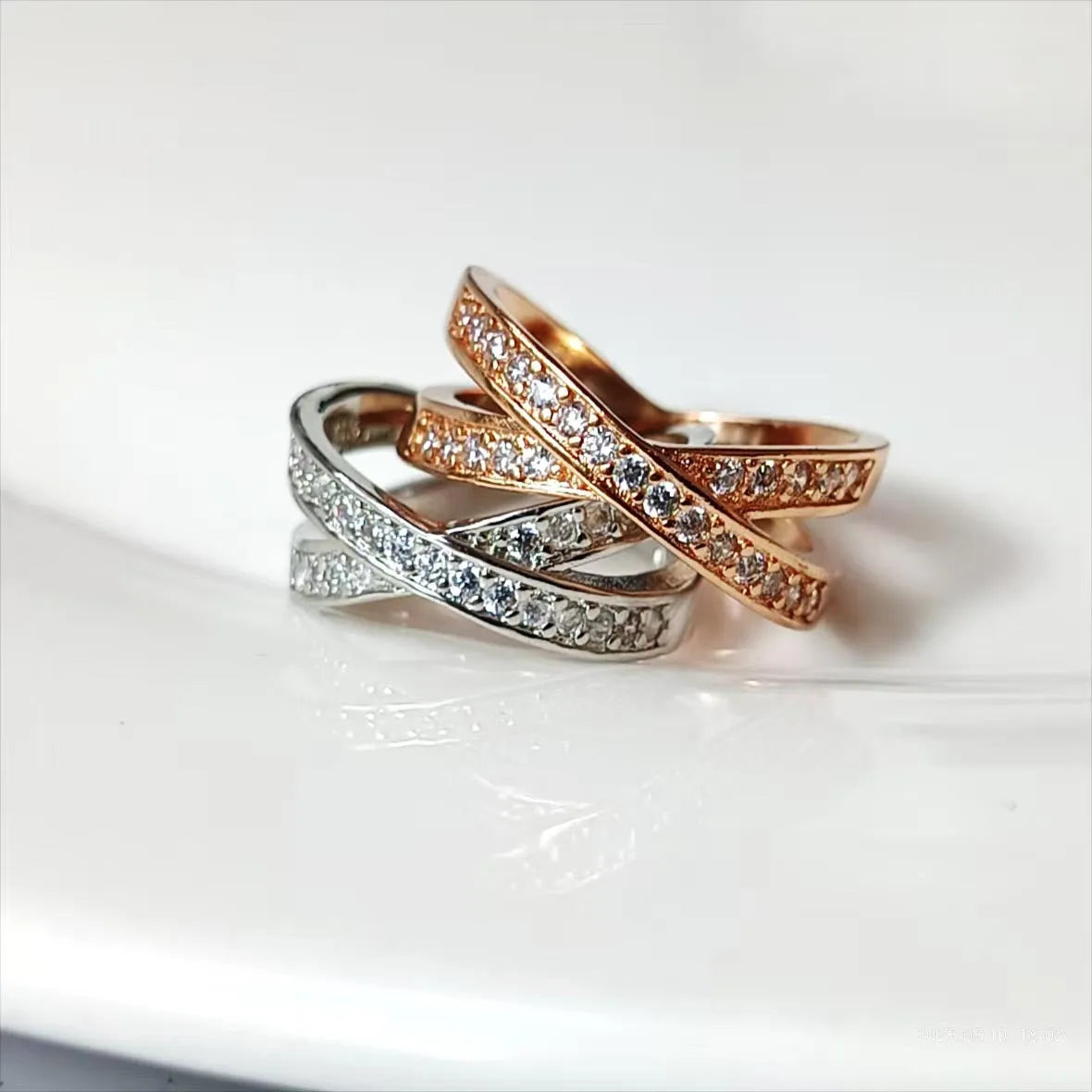 Geometric silver cross ring with micro-inlaid zircon stones on a model's finger.