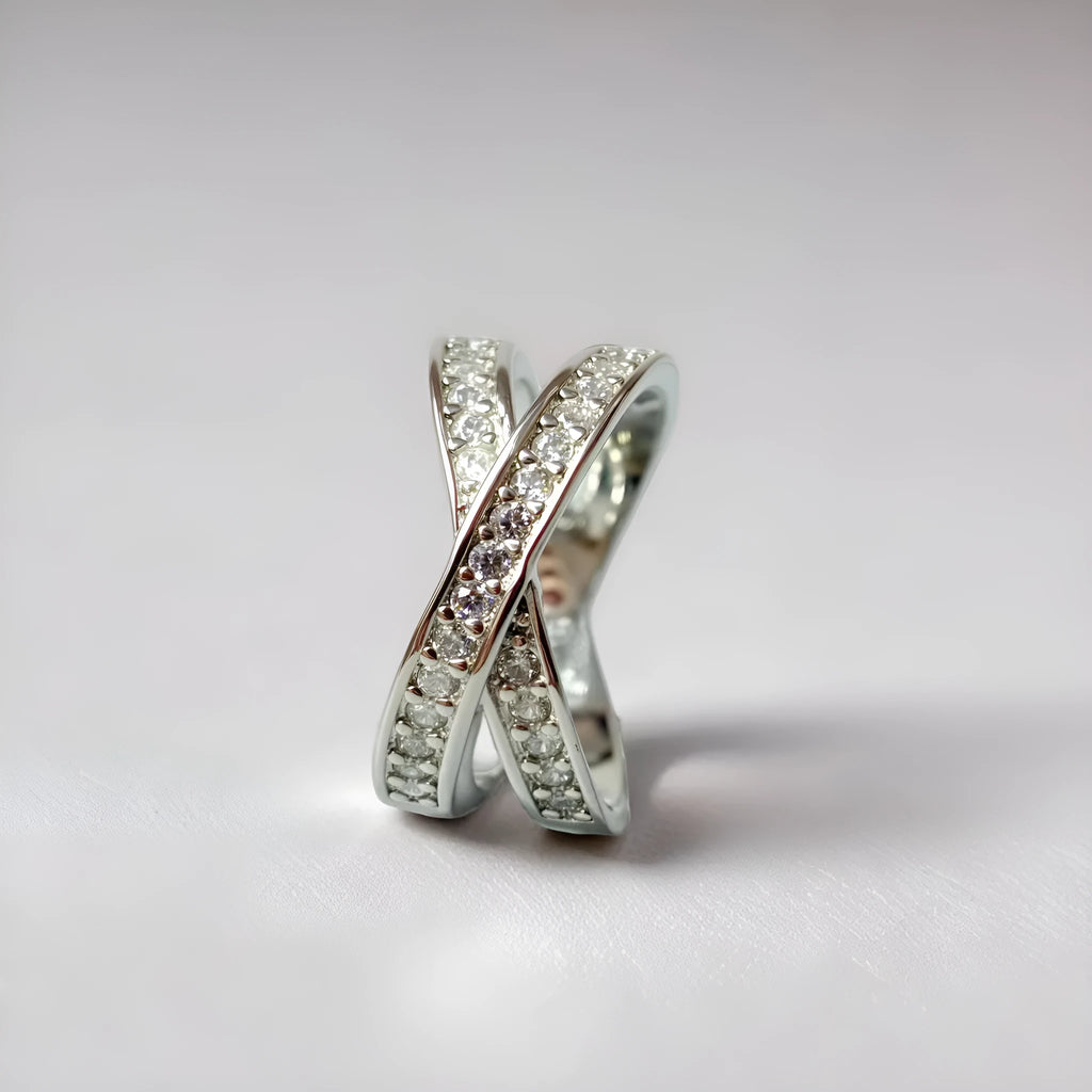 Geometric silver cross ring with micro-inlaid zircon stones on a model's finger.