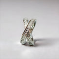 Geometric silver cross ring with micro-inlaid zircon stones on a model's finger.