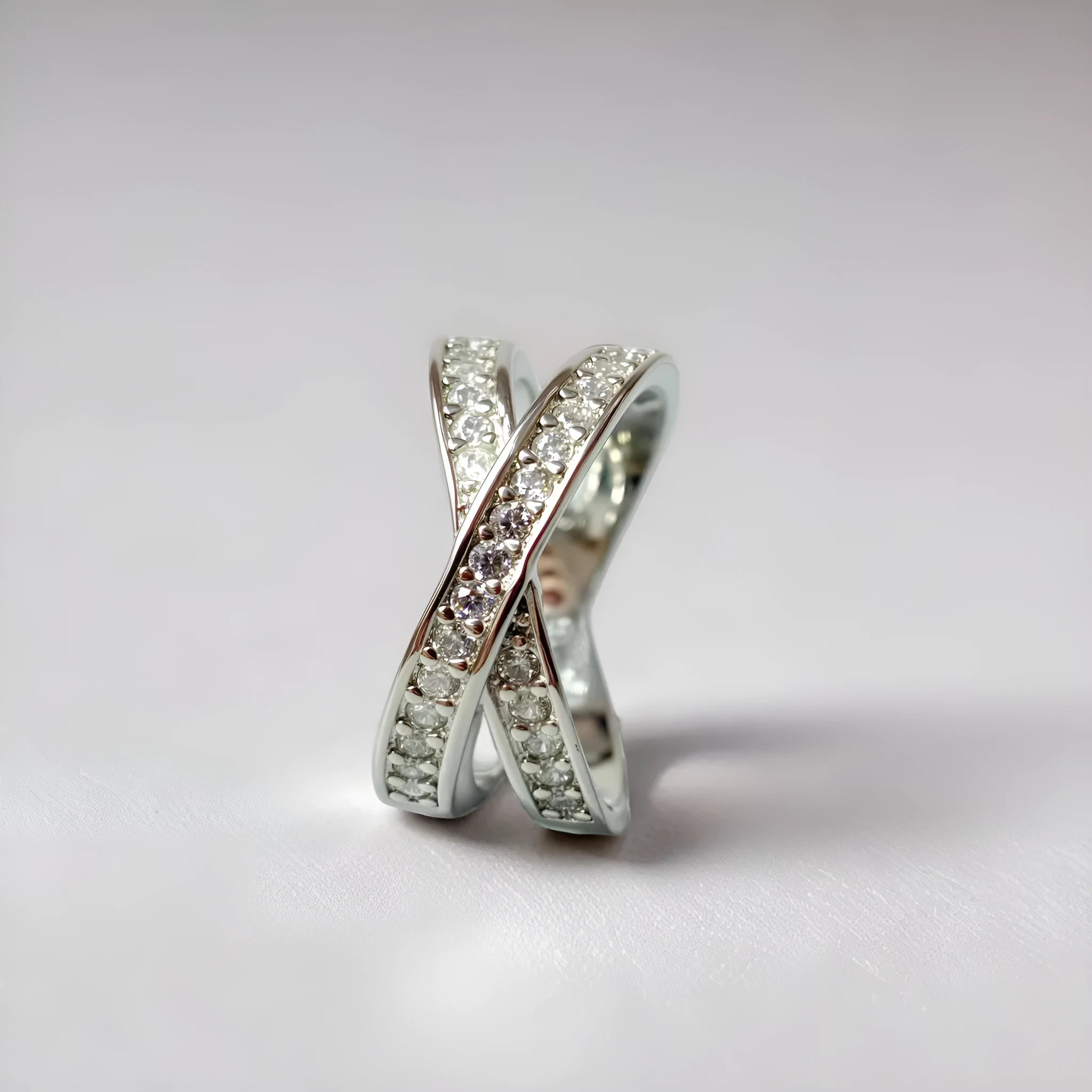 Geometric silver cross ring with micro-inlaid zircon stones on a model's finger.