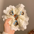 Close-up of a blue bow and bear cloth charm on a black elastic hair ring