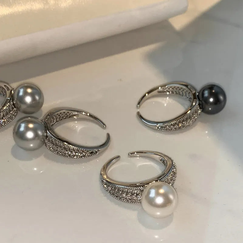 Geometric adjustable open ring in black pearl colour on a copper band, shown on a woman's index finger.