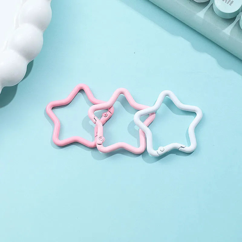 Zinc alloy five-pointed star keychain charm in assorted colours including light pink, blue, and black.