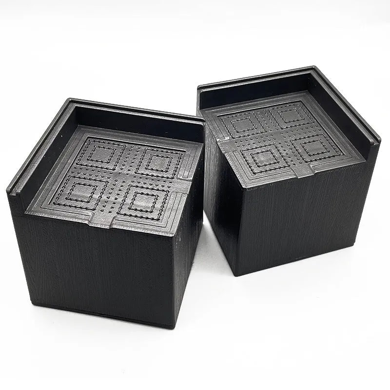 Four black plastic bed riser feet for increasing furniture height and creating storage space
