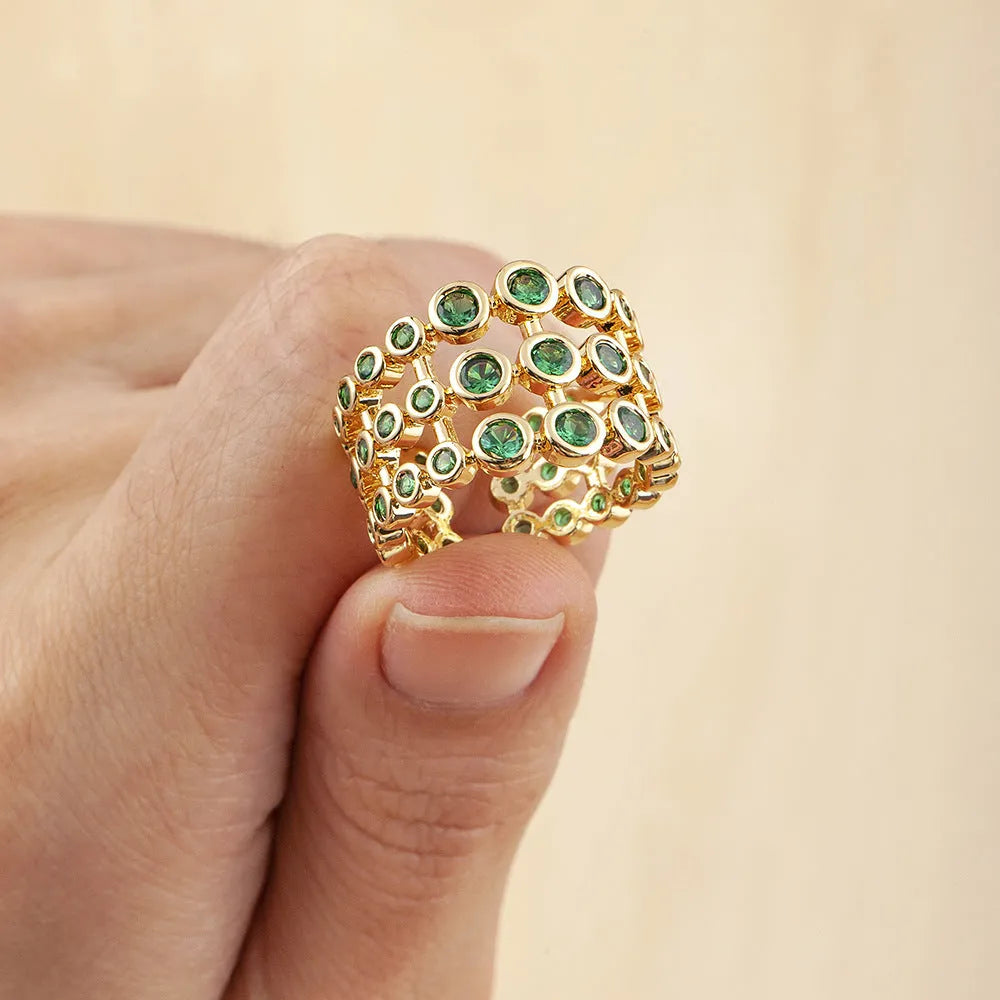 Copper ring with gold plating and green zircon stones in a wide exaggerated band.