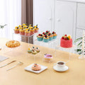 Set of six white plastic cube display stands arranged on a wooden tabletop.