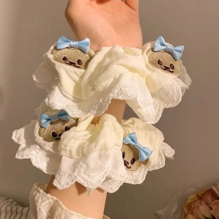 Close-up of a blue bow and bear cloth charm on a black elastic hair ring