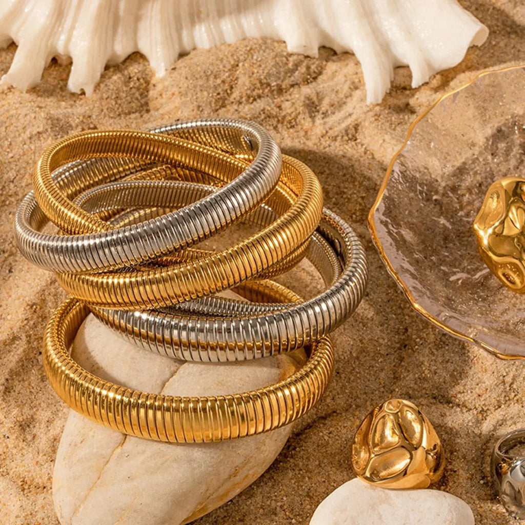 Women's gold titanium steel bracelet with exaggerated vertical stripe ring pattern and elastic band.
