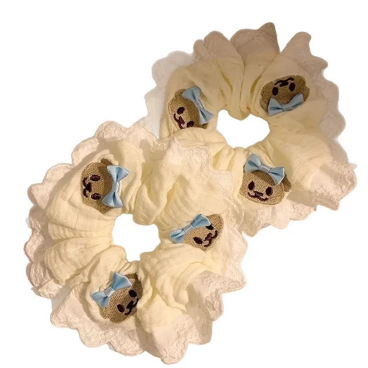 Close-up of a blue bow and bear cloth charm on a black elastic hair ring