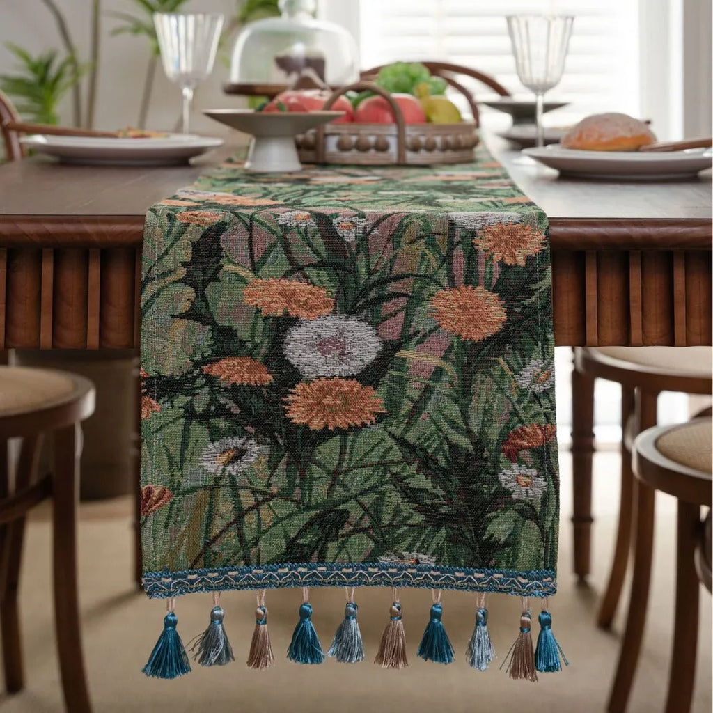 Long beige table runner with floral Jacquard pattern and tassels, shown on a wooden table.