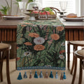 Long beige table runner with floral Jacquard pattern and tassels, shown on a wooden table.
