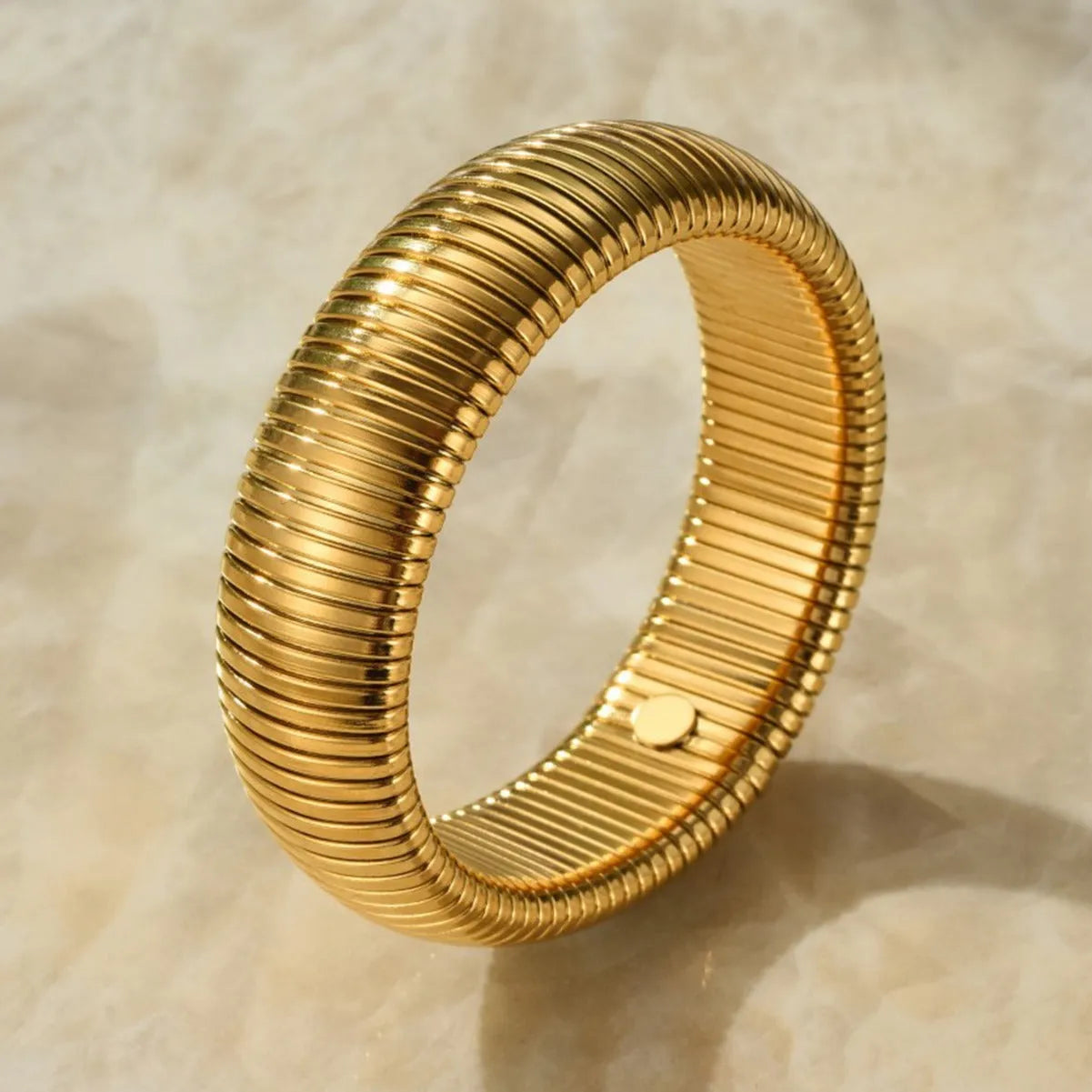 Women's gold titanium steel bracelet with exaggerated vertical stripe ring pattern and elastic band.