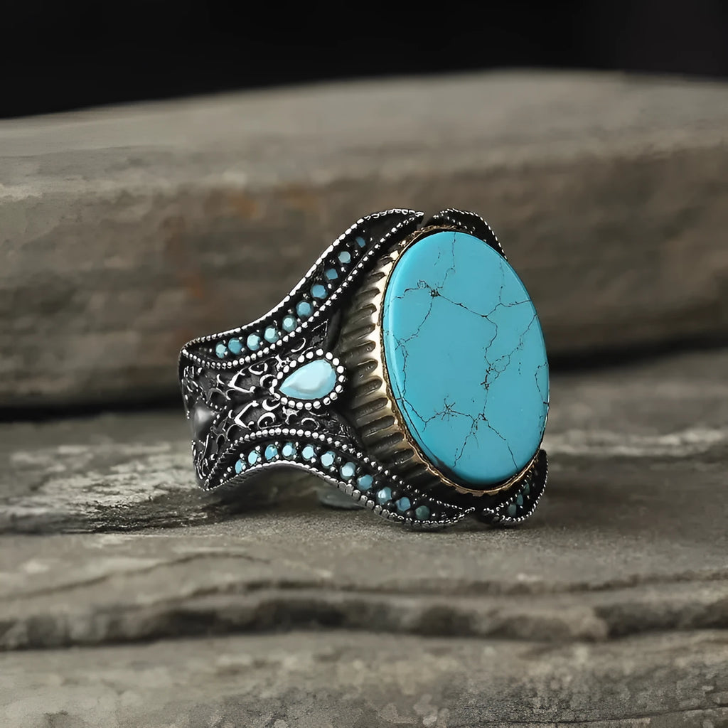 Men's antique silver alloy ring with a round band and a turquoise blue centrepiece on a hand.