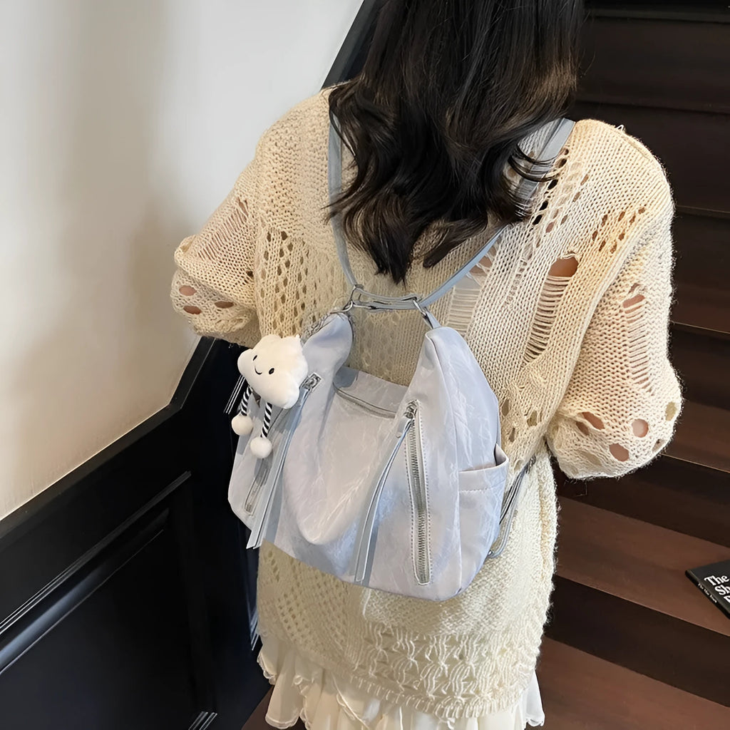 Soft black PU ladies fashion backpack with pendant, shown alongside blue, silver, and milky white colour options.