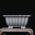 Square purple sand ceramic bonsai pot with warp device on a desktop.