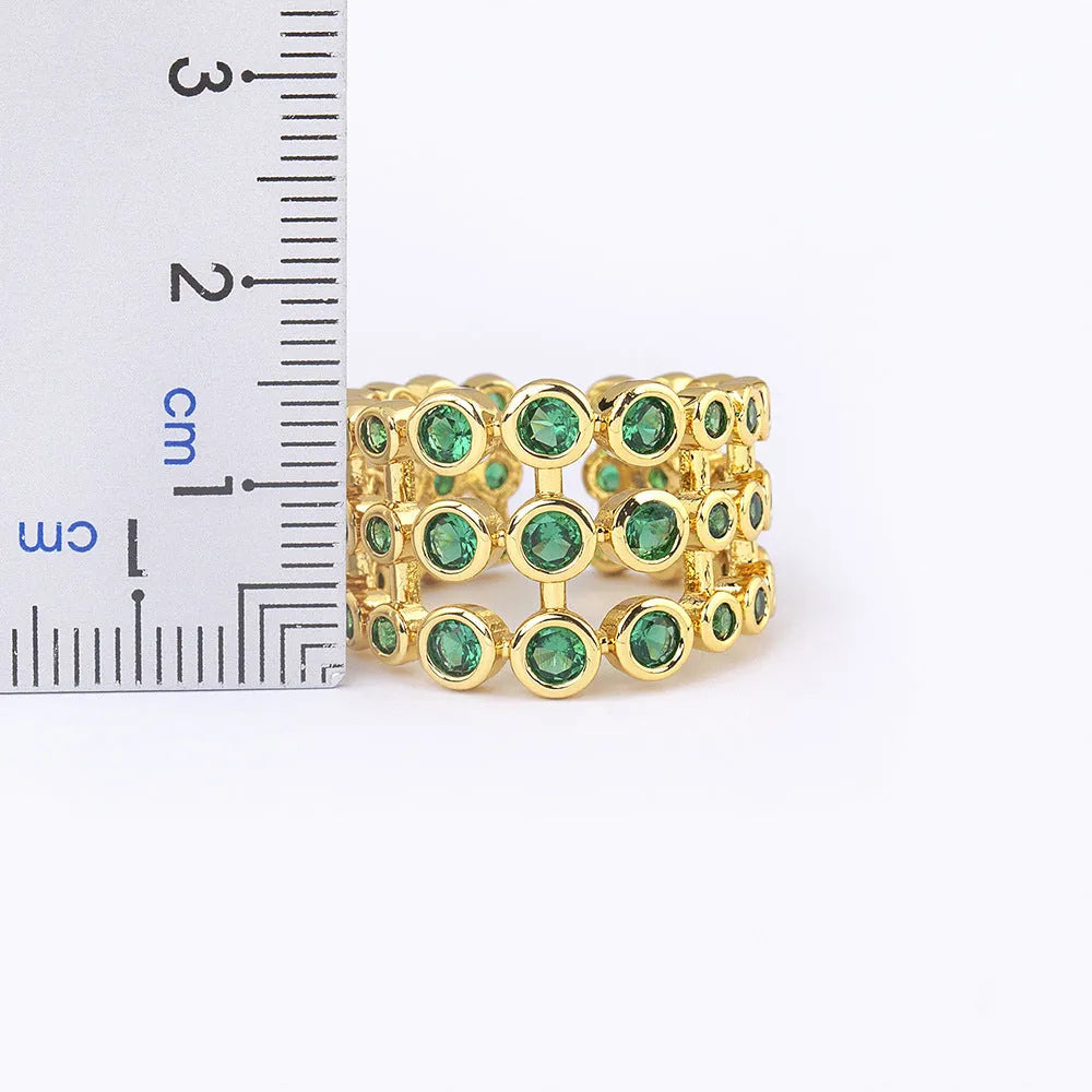 Copper ring with gold plating and green zircon stones in a wide exaggerated band.