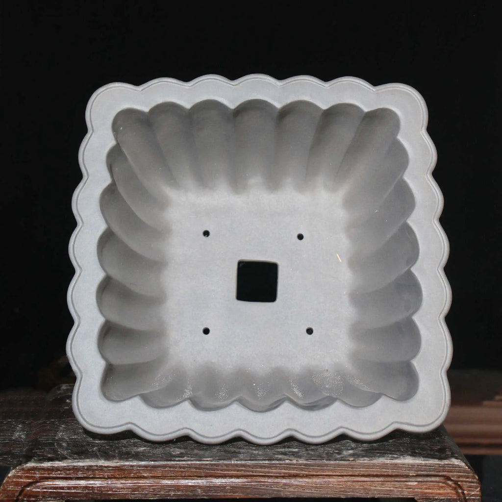 Square purple sand ceramic bonsai pot with warp device on a desktop.