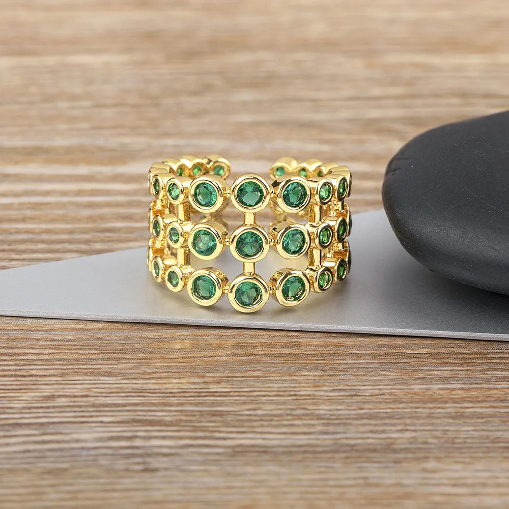Copper ring with gold plating and green zircon stones in a wide exaggerated band.