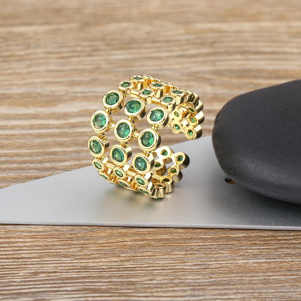 Copper ring with gold plating and green zircon stones in a wide exaggerated band.