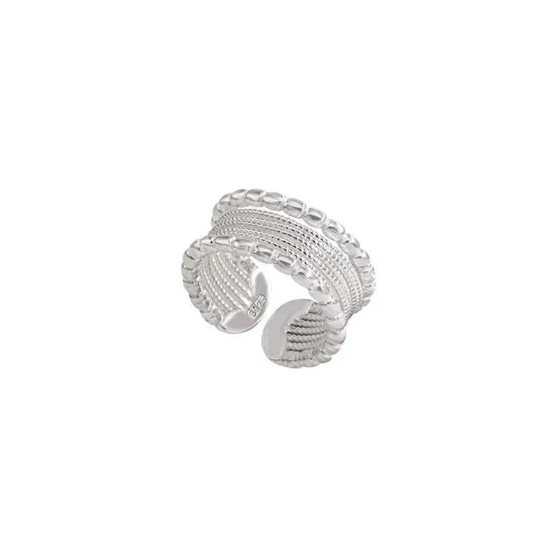 Copper adjustable ring with a woven twisted multilayer geometric design on a finger.