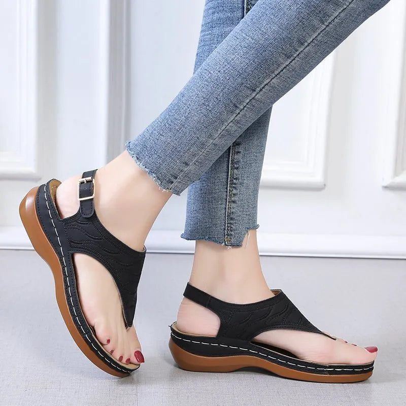 Women's black wedge heel sandals with an adjustable back strap buckle on a white background.