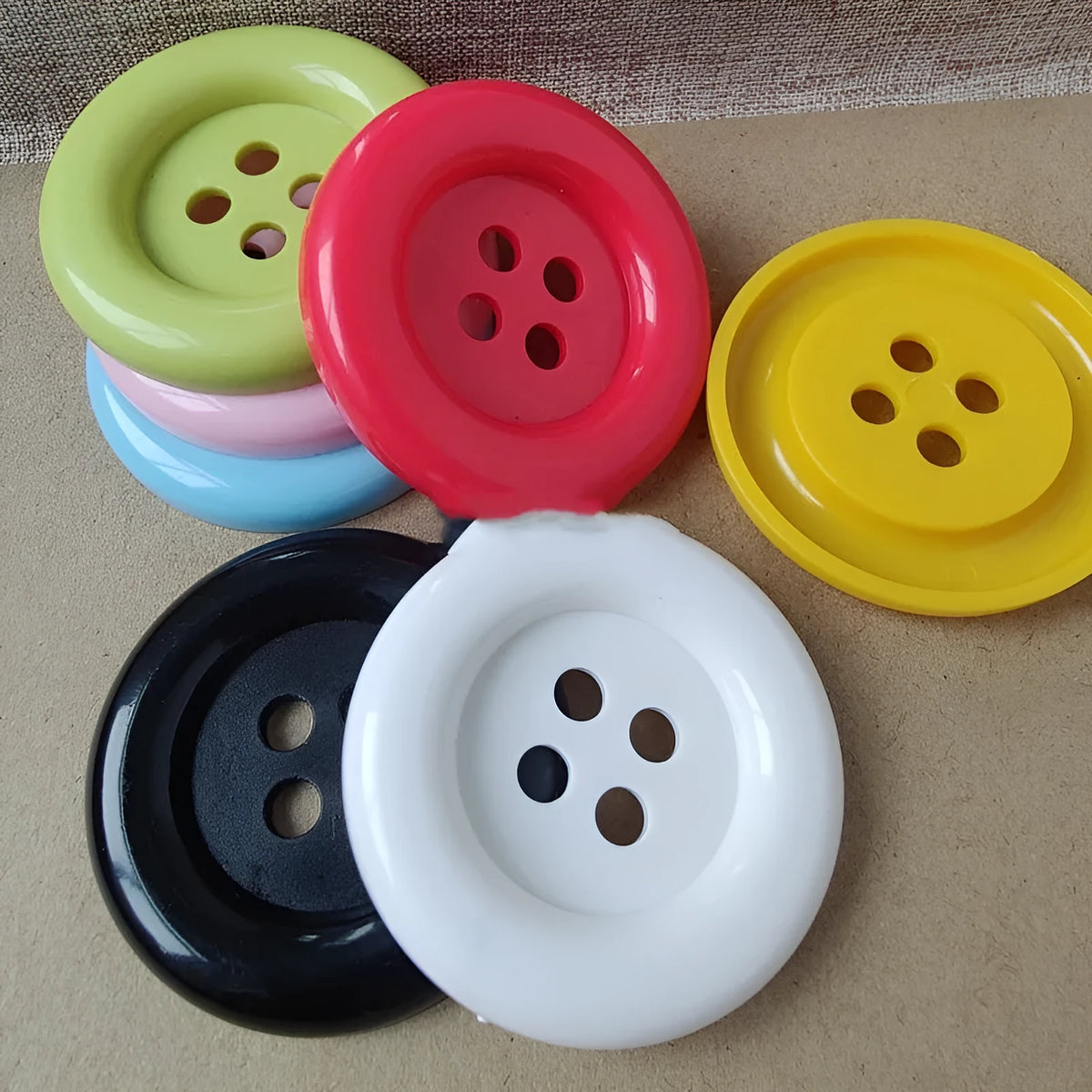 Assortment of large round plastic sewing buttons in multiple colours with four holes.