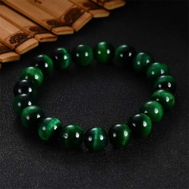 Green tiger eye stone bracelet with polished geometry beads on a wrist, showing the stone's natural banding.