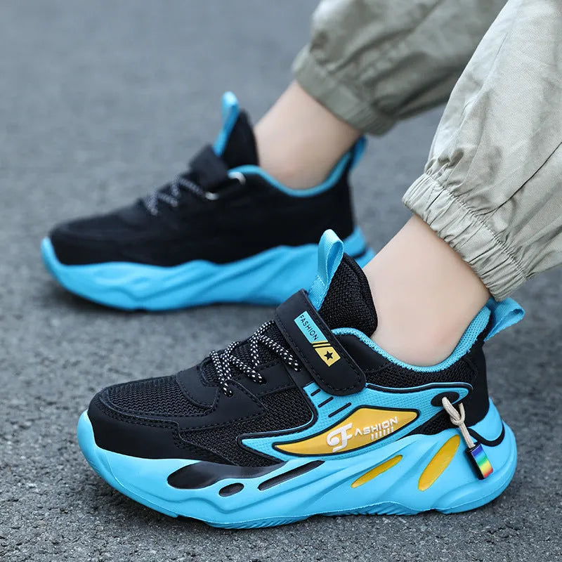Boys' blue and black platform sports running shoes with Velcro straps on a hard ground surface.